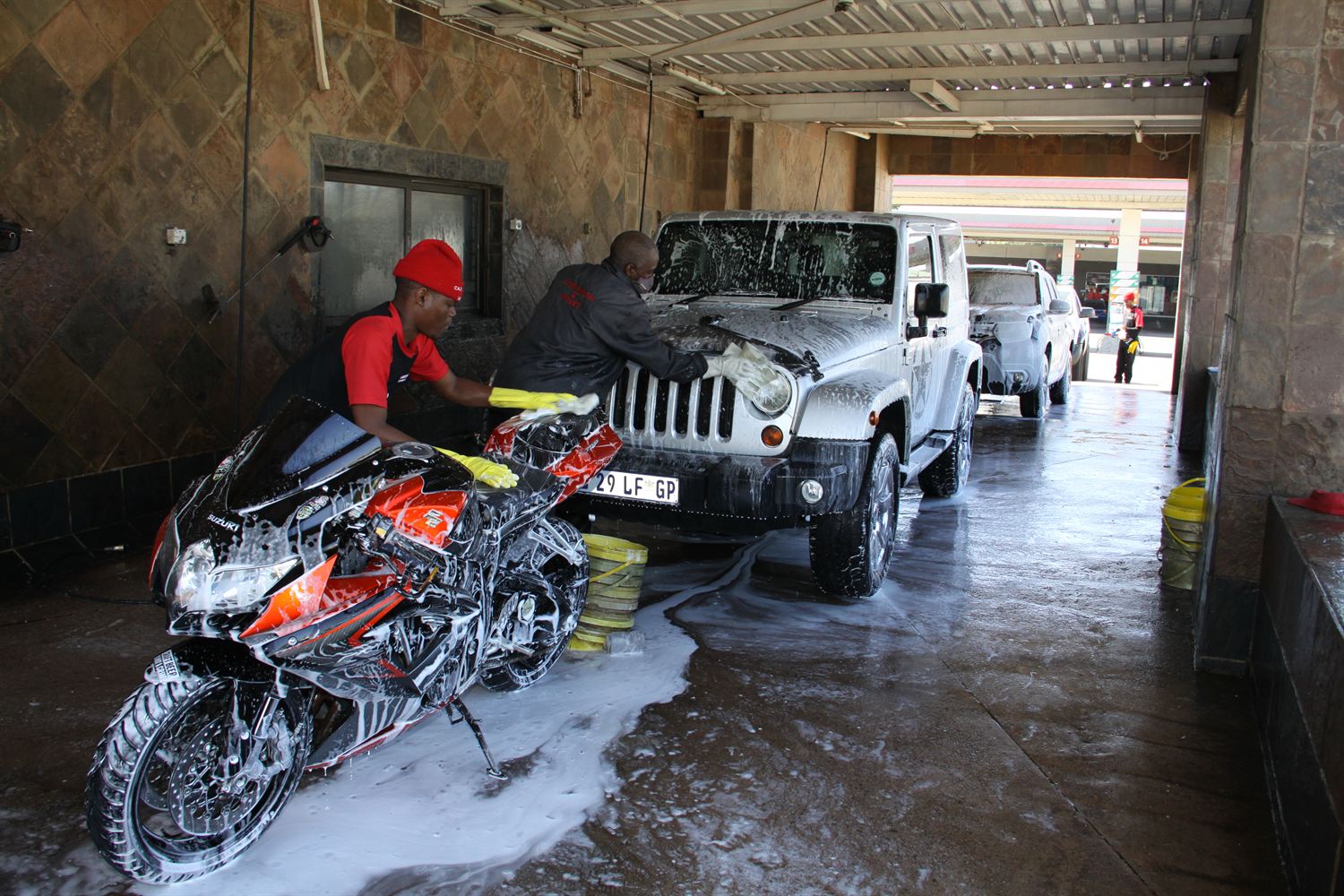 Hand washing a foam-covered bike and vehicle at Kilner Park Car Wash